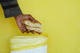 A man throwing bread in a dustbin