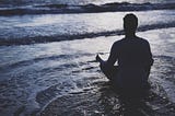 Man in lotus pose on a beach