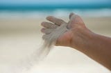 A handful of sand being released as we release our desires