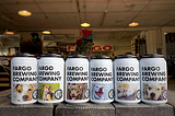 Cans of beer from Fargo Brewery that feature pictures of shelter dogs that need homes