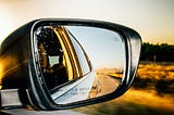 A side view mirror from a car, while the car is traveling on a road.