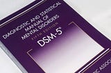 This is a photo of the front cover of the American Psychiatric Association’s Dianostic and Statistical Manual of Mental Disorders, Fifth Edition.