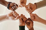 Six fits of diverse races joined together around a circle in solidarity