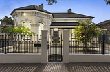 A white house with a black gate and a white fence in north adelaide.