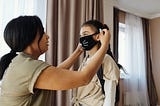 Parent Placing Mask on Child for School
