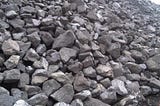 A large pile of chromite ore rocks ready for processing.