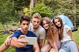 Teenagers in front of tent camping in forest.