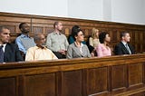 Ordinary people sitting in a jury box in a wood-panelled courtroom