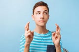 Teenage boy with fingers crossed, wishing for something.
