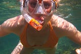 An underwater woman in snorkel gear poses