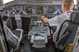 View of an airplane cockpit with a pilot checking the instrument panel