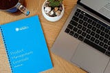 Little blue book from Mind the product next to a laptop on a desk.
