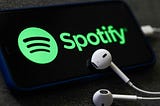 An image of a mobile phone with a Spotify logo and headphones.