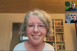 A screenshot from a podcast recording featuring Katrin Langensiepen as the main speaker. She is a middle-aged woman with short, curly gray hair, wearing glasses and a light-colored top, smiling at the camera. Behind her is a bookshelf filled with books and decorative items. In the top-right corner, two smaller video windows show the podcast hosts; one is wearing glasses and a dark jacket, with a blurred outdoor background, while the other is in a room with framed pictures on the wall, wearing a black shirt.