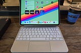 An 11-inch M4 iPad Pro on a wooden desk, attached to a white magic keyboard.