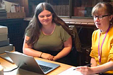 two women in front of a laptop, one has a pencil