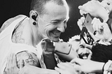 Chester Bennington smiling towards fans with phone cameras in front of him.