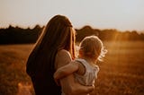 Mother holding her kid at sunset