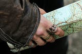 Person holding a map looking like they’re about to search for treasure