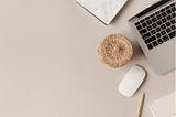 Aesthetic stock image of a desk flat lay featuring a laptop, mouse, pencil and notebook. The image is purely for decorative use only to support the blog post on how to set value-driven goals