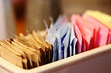 Different colorful packets of artificial sweeteners and sugars