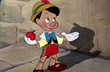 Pinocchio, a wooden boy puppet from the 1940s animated Disney film, proudly holds an apple.