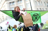 A guy having fun protesting for the environment, with a cardboard saying: “I’m a scientist and this is completely necessary”