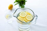 A pitcher of water with lemon slices is sitting on a white countertop.