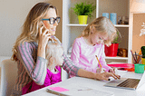 Lady working from home while children entertain themselves at her desk