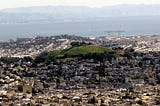 photo of Bernal Heights, San Francisco, with San Francisco Bay and the Easy Bay in the background, and a cloud shadow.