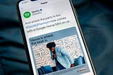 An image of a phone displaying a promoted tweet from Spotify.