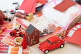 unorganized desk with red car, house, and misc items