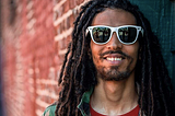 Question smiling at the camera, with a red t-shirt and white sunglasses on