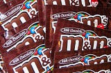Pile of brown M&M’s milk chocolate bags overlapping each other.