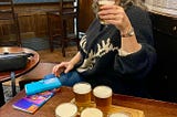 Woman sitting at a pub table with six small glasses of beer