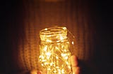two hands holding a jar with fairy lights
