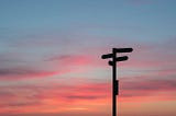 A signpost in frond of a sunset. Meta-analysis can help point policy analysts in the right direction.
