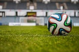 Uma bola num gramado, num estádio vazio.