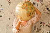 Woman holds world globe in front of face