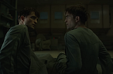 Robert Pattinson as both Mickey 17 and 18, sitting on a bed, looking at each other.