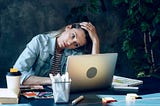 Woman with a laptop appears overworked and stressed out