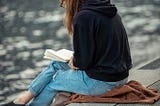 WOMAN READING BY THE WATER