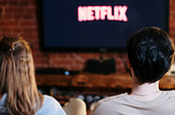 couple from behind watching Netflix on their TV