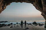 man and woman in silouette facing the beach from the perspective of someone standing behind them, modern marriage