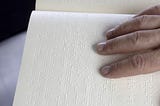 Image show a person’s hands as they read braille