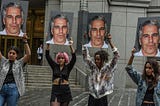 Victims of Jeffrey Epstein holding up big images of his face