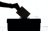 Hand dropping a ballot into a ballotbox