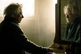 An elderly man stands before a bathroom mirror at dawn while his reflection lingers just slightly behind his movements, creating a subtle but deeply unsettling sense that the two are no longer the same person.