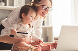 Mom Holding Son While Looking At Laptop