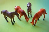 Four toy horses photographed on a green background